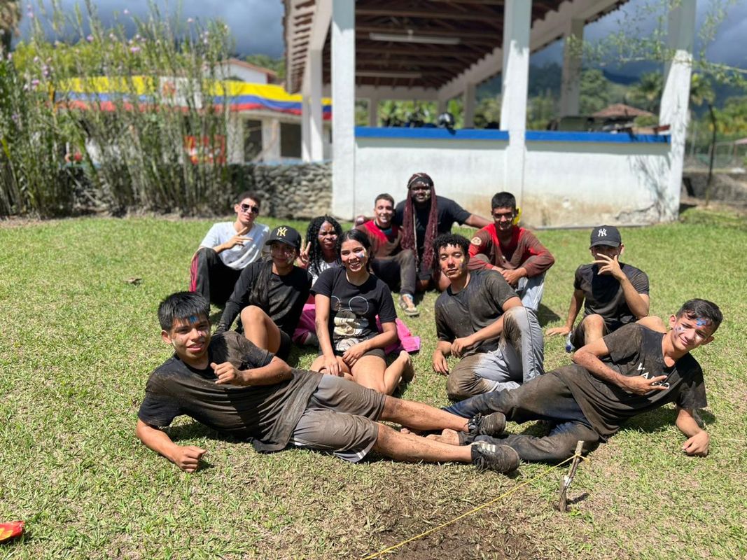 Jóvenes de MATAÜA descansando sobre el pasto después de la actividad de barro